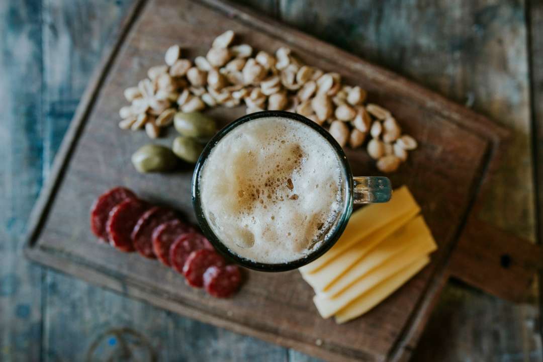 Dettaglio con boccale di birra e tagliere di affettati e formaggi.