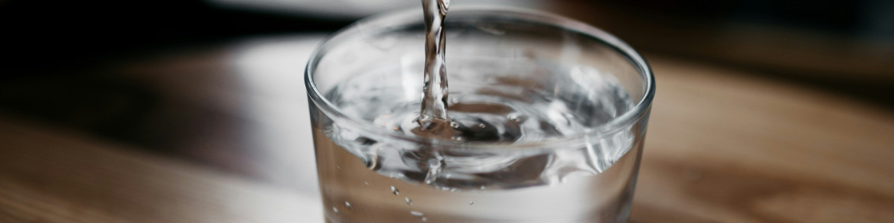 Acqua versata in un bicchiere da una bottiglia di vetro, dettaglio, PD distribuzione.