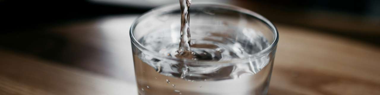 Acqua versata in un bicchiere da una bottiglia di vetro, dettaglio, PD distribuzione.